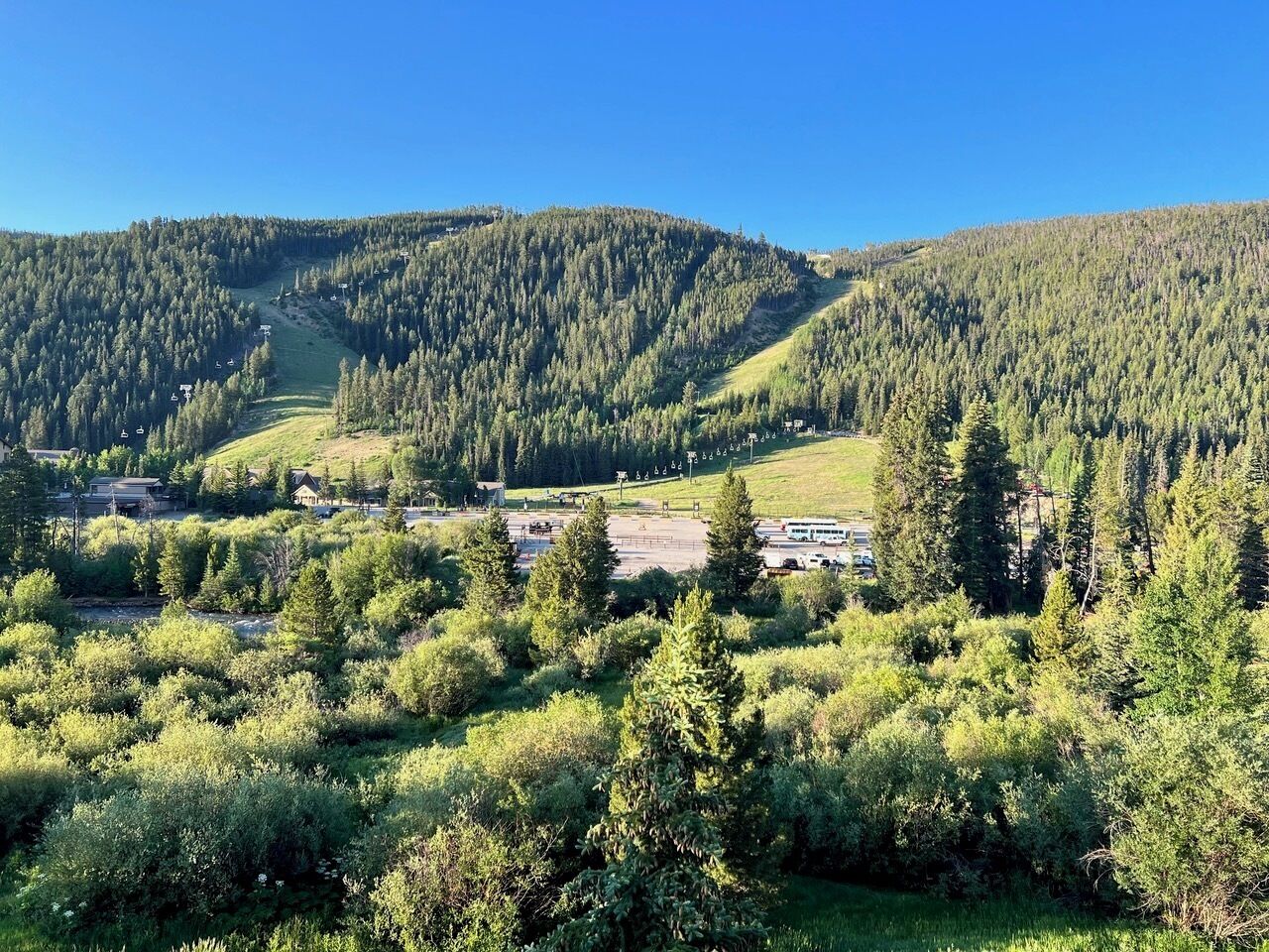 Paesaggio montano con una stazione sciistica, che include edifici e impianti di risalita.