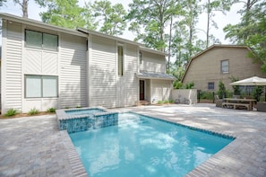 A two-story house with a swimming pool, a patio, and a bicycle.