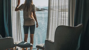 Una habitación con un ventanal, vista a un cuerpo de agua y dos sillas.