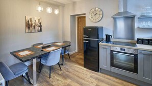 A modern kitchen with a black refrigerator, stainless steel oven, and a clock on the wall. - Host & Stay | 82F Galgate (Barnard Castle)
