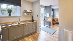 A modern kitchen with grey cabinets, a large window, and a view into the living area. - Host & Stay | 82F Galgate (Barnard Castle)