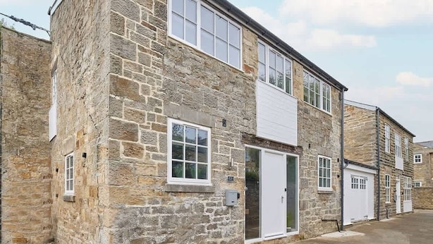 A stone building with a white door and windows, likely a residential property. - Host & Stay | 82F Galgate (Barnard Castle)