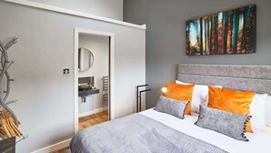 A bedroom with a bed, a headboard, a painting, and a door leading to a bathroom. - Host & Stay | 82F Galgate (Barnard Castle)