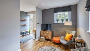 A modern living room with a grey sofa, a rocking chair, a TV, and a fireplace. - Host & Stay | 82F Galgate (Barnard Castle)
