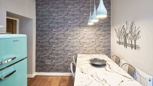 Uma cozinha moderna com painel de parede de pedra, bancada de mármore e geladeira azul antiga.