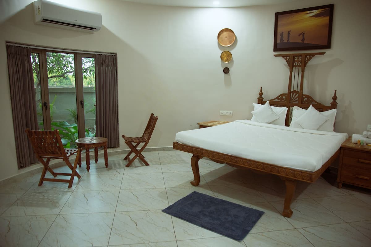 Une chambre avec un grand lit, une chaise, une petite table et une vue par la fenêtre.