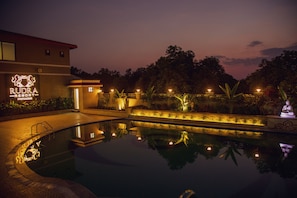 A swimming pool at night with a building labeled "RUDRA Resort" in the background.