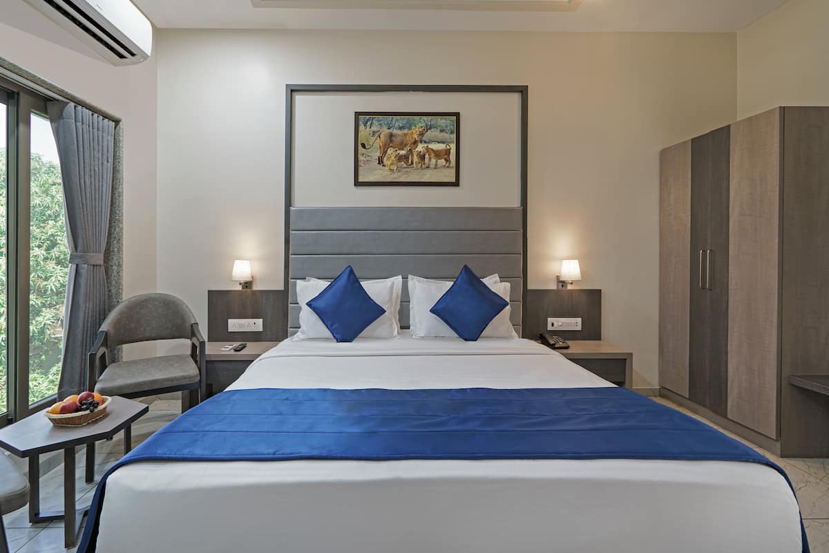 Une chambre d’hôtel avec un grand lit, deux tables de chevet, un bureau, une chaise, une armoire et un tableau au mur.