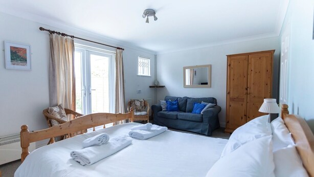 Un dormitorio con una cama grande, un armario de madera, un sofá gris y una silla.