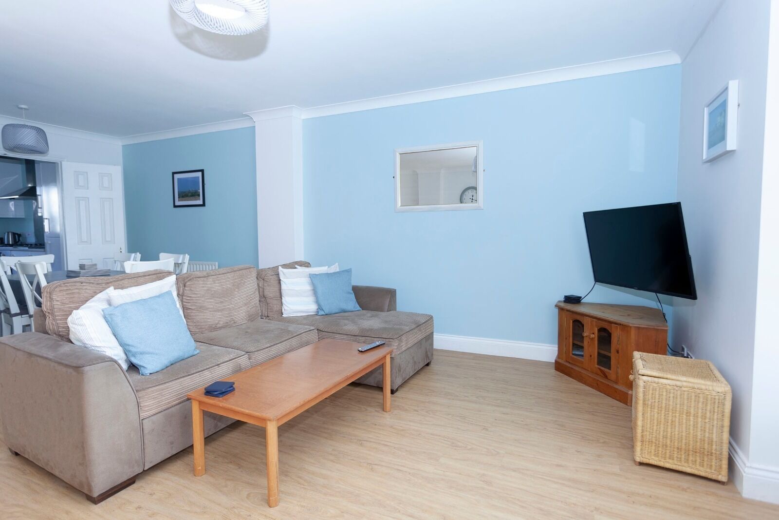 A living room with a sectional sofa, a coffee table, a television, and a wicker basket.