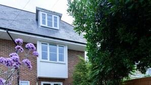 Un patio con una mesa y sillas, un cobertizo y una casa de ladrillo con una ventana.