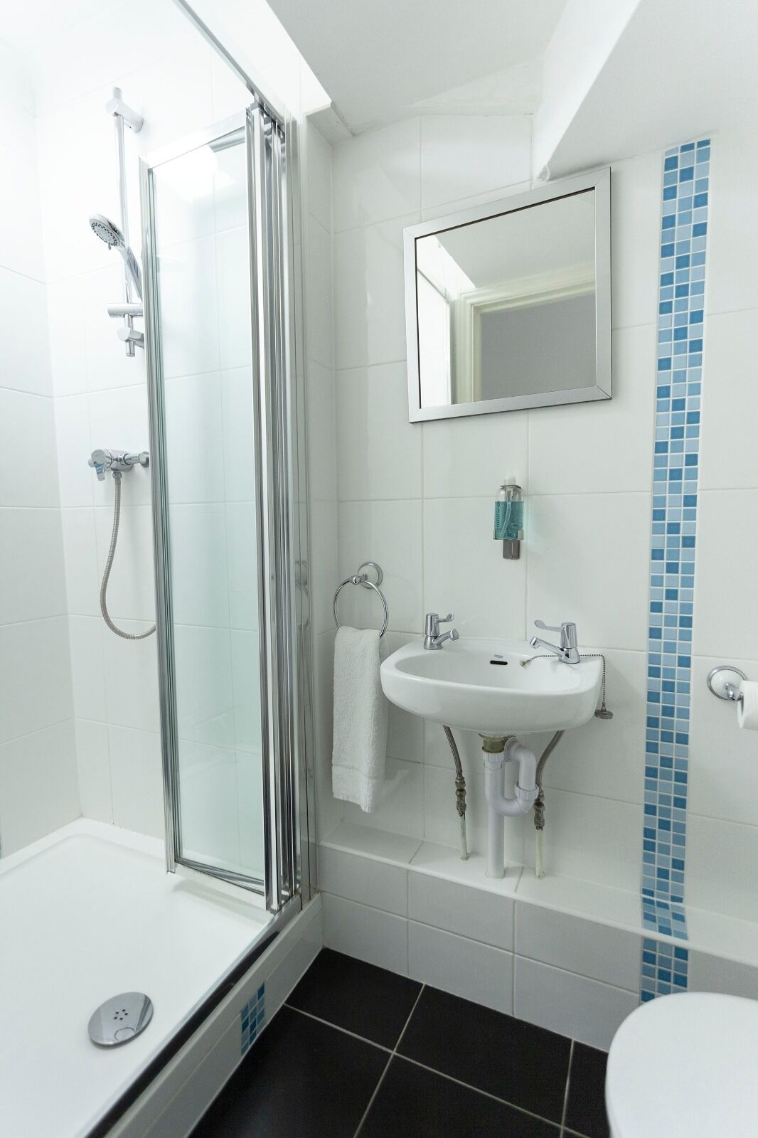 A modern bathroom with a glass-enclosed shower, a white sink with a mirror above it, and a toilet.