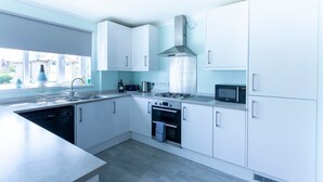 Una cocina moderna con gabinetes blancos, estufa a gas, microondas y lavavajillas.