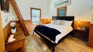 A bedroom with a wooden bed, two windows with blinds, a bedside table with a lamp, and a small potted plant. - Lazy Bear Bungalow Pet Friendly Lake Escape  (Truckee)
