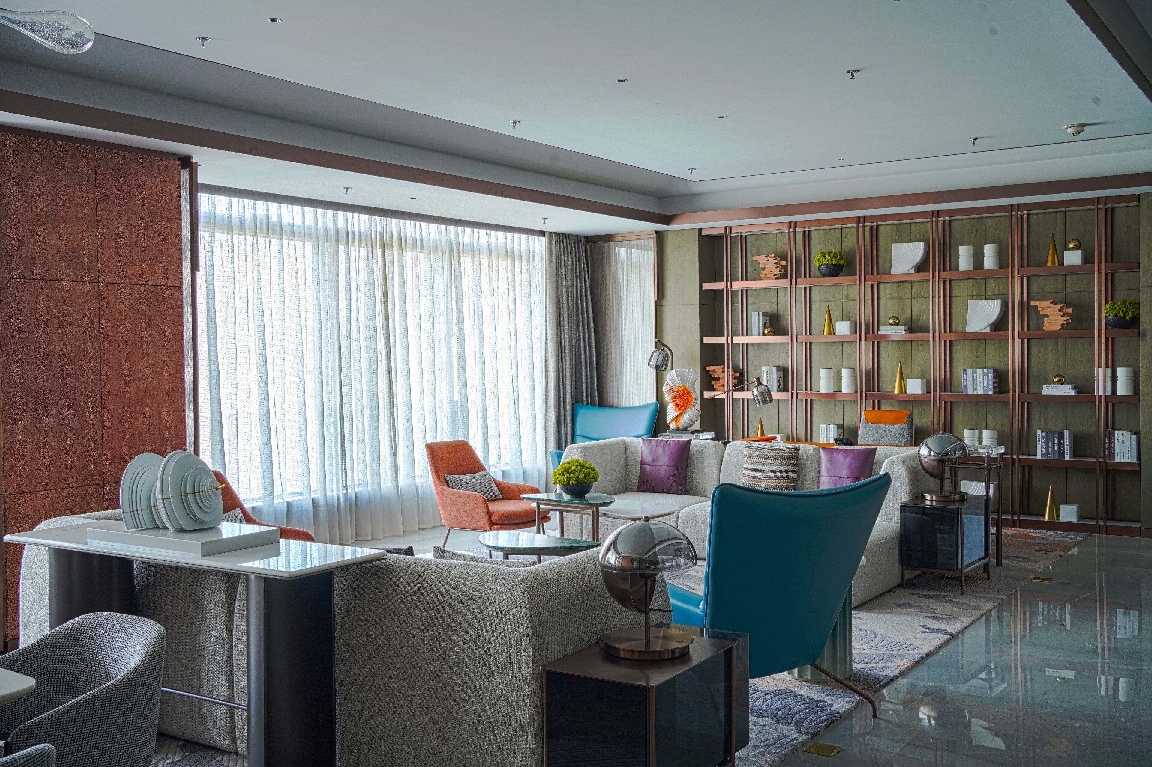 Una sala de estar moderna con un sofá, sillones, una mesa de centro y una estantería.