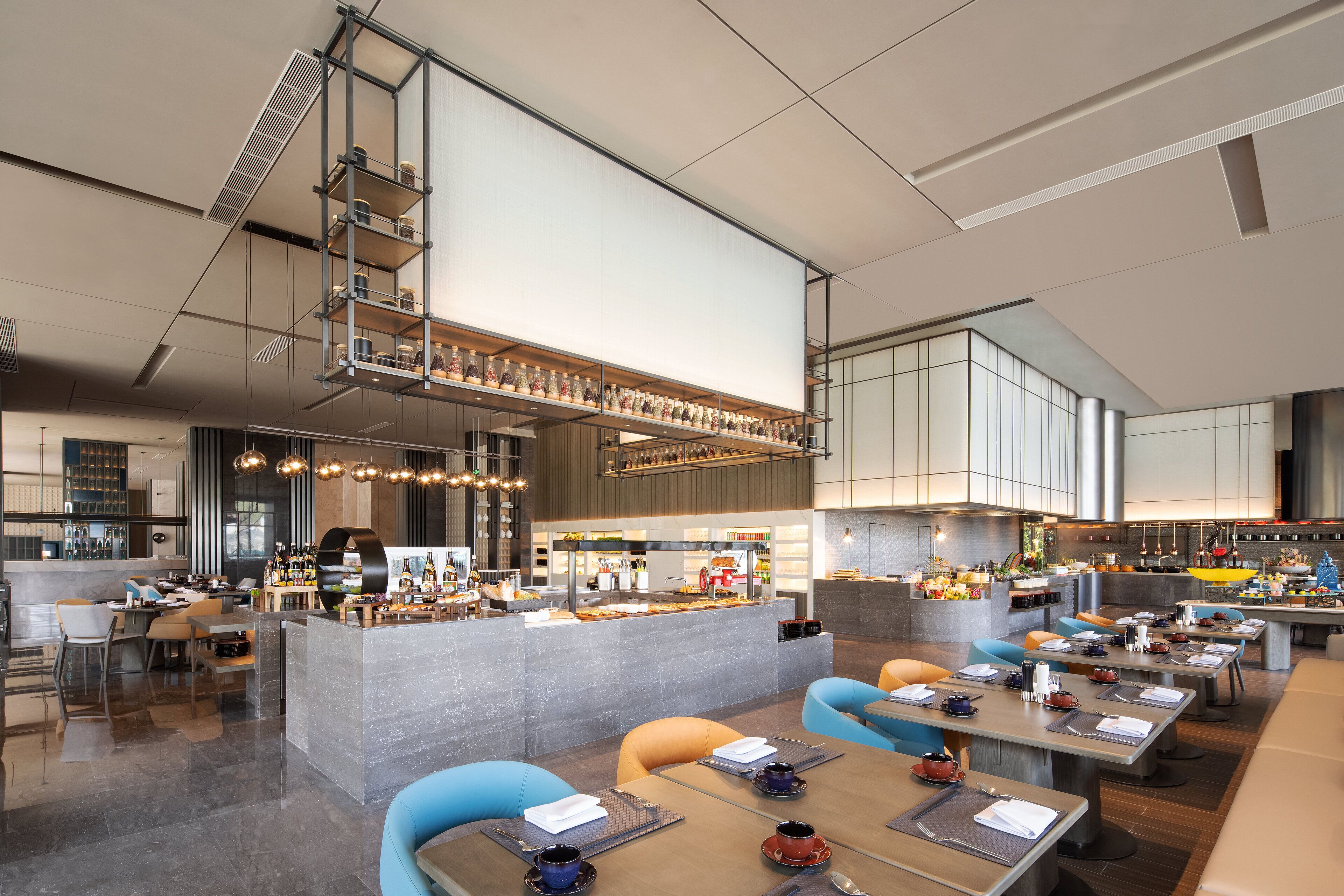 A modern restaurant with a central bar area, multiple seating options, and a high ceiling with exposed ductwork.