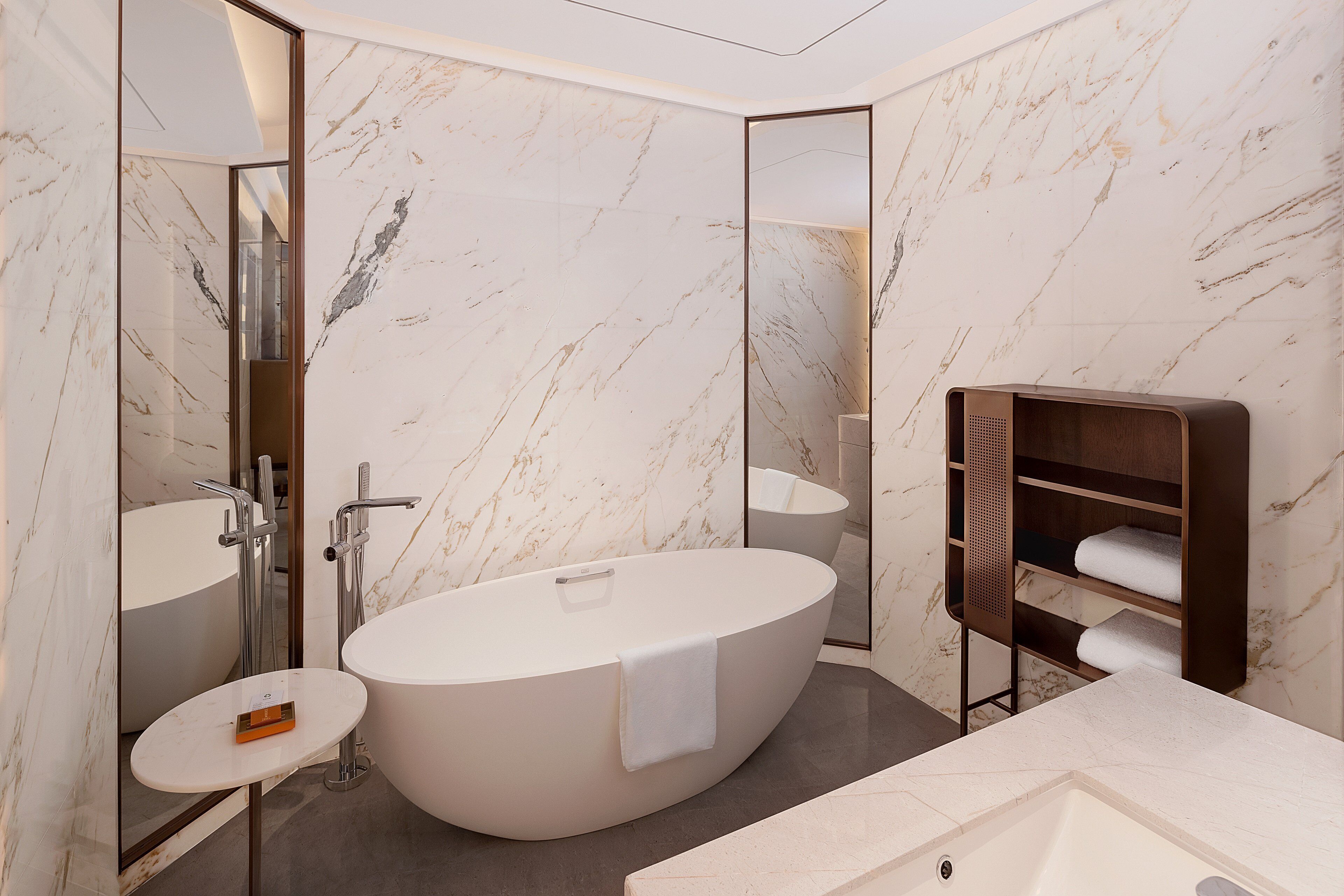 A modern bathroom with a freestanding bathtub, a small sink, and a towel rack.