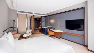 Una camera d'albergo moderna con un letto grande, una scrivania, una sedia, una TV e un armadio.