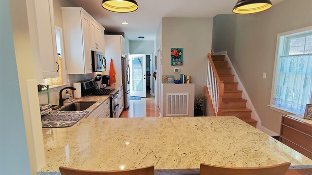 A kitchen with a central island, wooden chairs, and pendant lighting. - Large Luxury 4 bed/3 bath Beach House-2 Blocks to beach, 1 Block to Bay (Colonial Beach)
