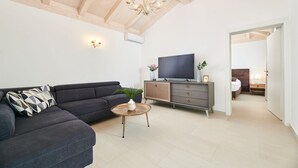 A modern living room with a dark grey sofa, a wooden coffee table, and a TV on a wooden cabinet.