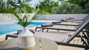 A poolside area with lounge chairs and a potted plant.
