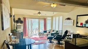 Een ruime woonkamer met een eettafel, stoelen, een bank en een plafondventilator.