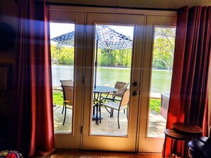 Ein Zimmer mit einer Schiebetür, die auf eine Außenpatio mit Tisch, Stühlen, einem kleinen runden Tisch und einem Zierteil-Sonnenschirm führt.