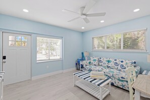 Una habitación con ventilador de techo blanco, una puerta blanca y una ventana con persianas.