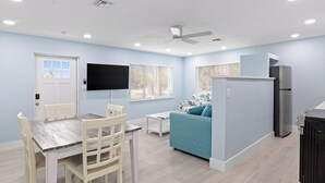 A compact living space with a dining area, a sofa, a TV, and a refrigerator.