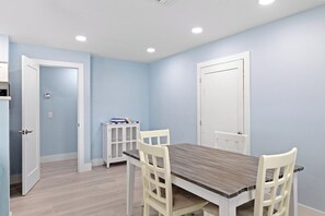 Une pièce comprenant une table à manger, des chaises, un buffet et deux portes.