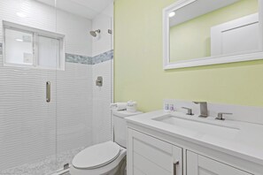 A bathroom with a shower, toilet, sink, and mirror.