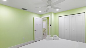A bedroom with a bed, a ceiling fan, a white door, and a closet. - Pirates Cove Cottage at Palmview Inn of Sanibel (Sanibel)