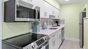 A modern kitchen with stainless steel appliances, white cabinetry, and a patterned backsplash. - Pirates Cove Cottage at Palmview Inn of Sanibel (Sanibel)
