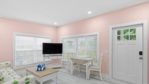 Una sala de estar con televisor, mesa de centro, sofá y una puerta.