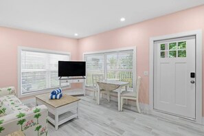 Ein Wohnzimmer mit Fernseher, Couchtisch, Sofa und einer Tür.