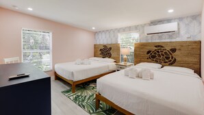 Habitación de hotel con dos camas, un escritorio y aire acondicionado instalado en la pared.