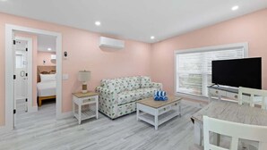 Una habitación con cama, sofá, televisor, mesa de centro y mueble para televisión.
