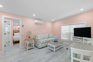 Ein Zimmer mit einem Bett, einem Sofa, einem Fernseher, einem Couchtisch und einem TV-Schrank.