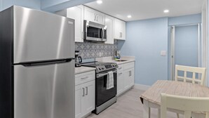 Una cocina compacta con refrigerador, microondas, estufa y horno de acero inoxidable.