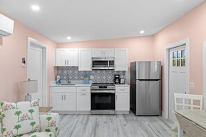 A compact kitchen with white cabinets, a stainless steel oven, and a refrigerator.