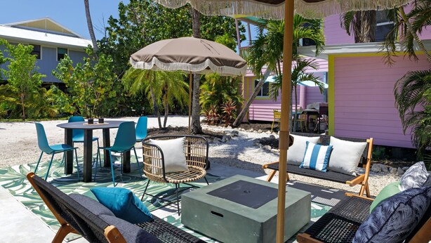 En udendørs terrasse med et bord, stole, en gyngestol og et overdækket siddeområde.