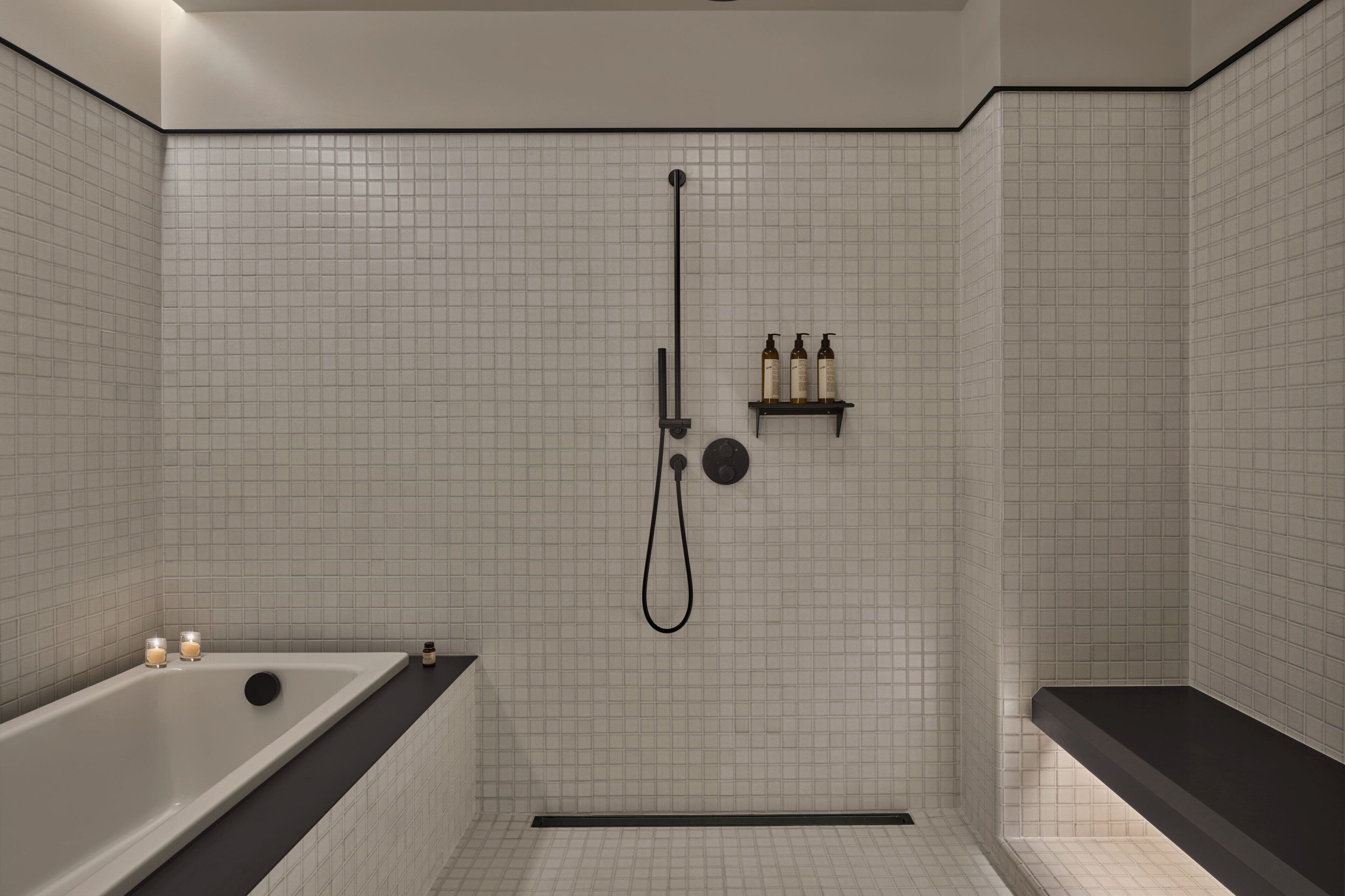Uma casa de banho moderna com banheira, chuveiro e um espaço de arrumação com produtos de higiene pessoal.