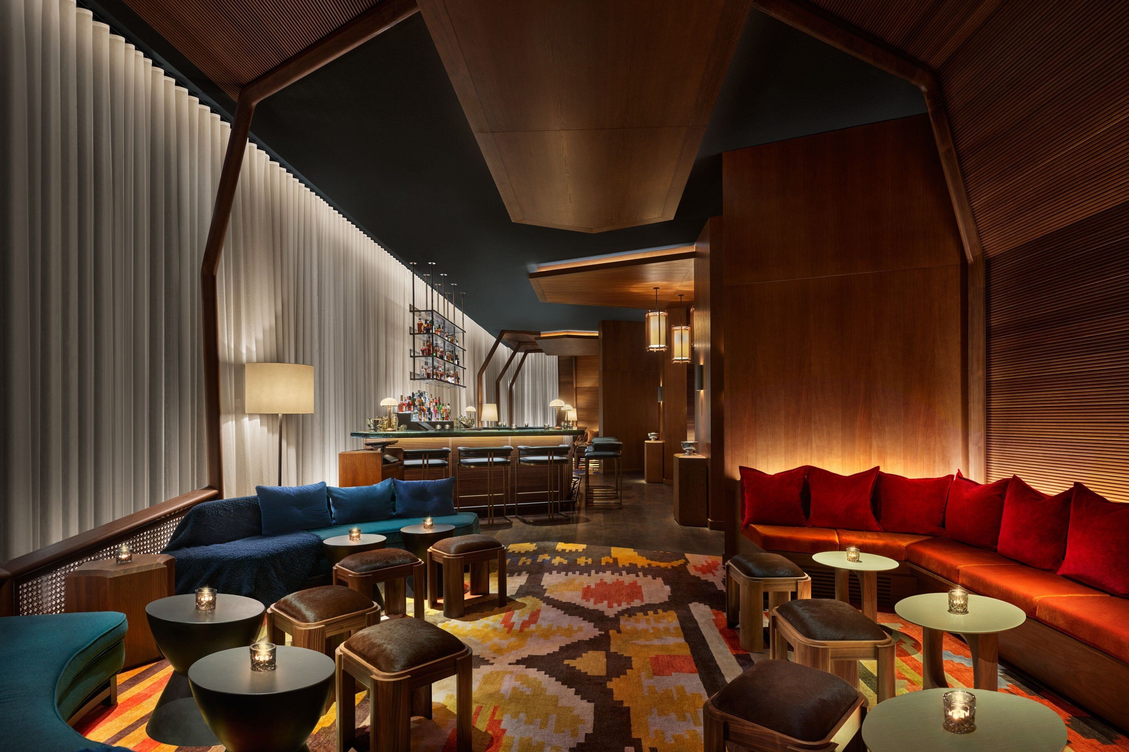 A modern lounge area with a bar, seating arrangements, and a patterned carpet.