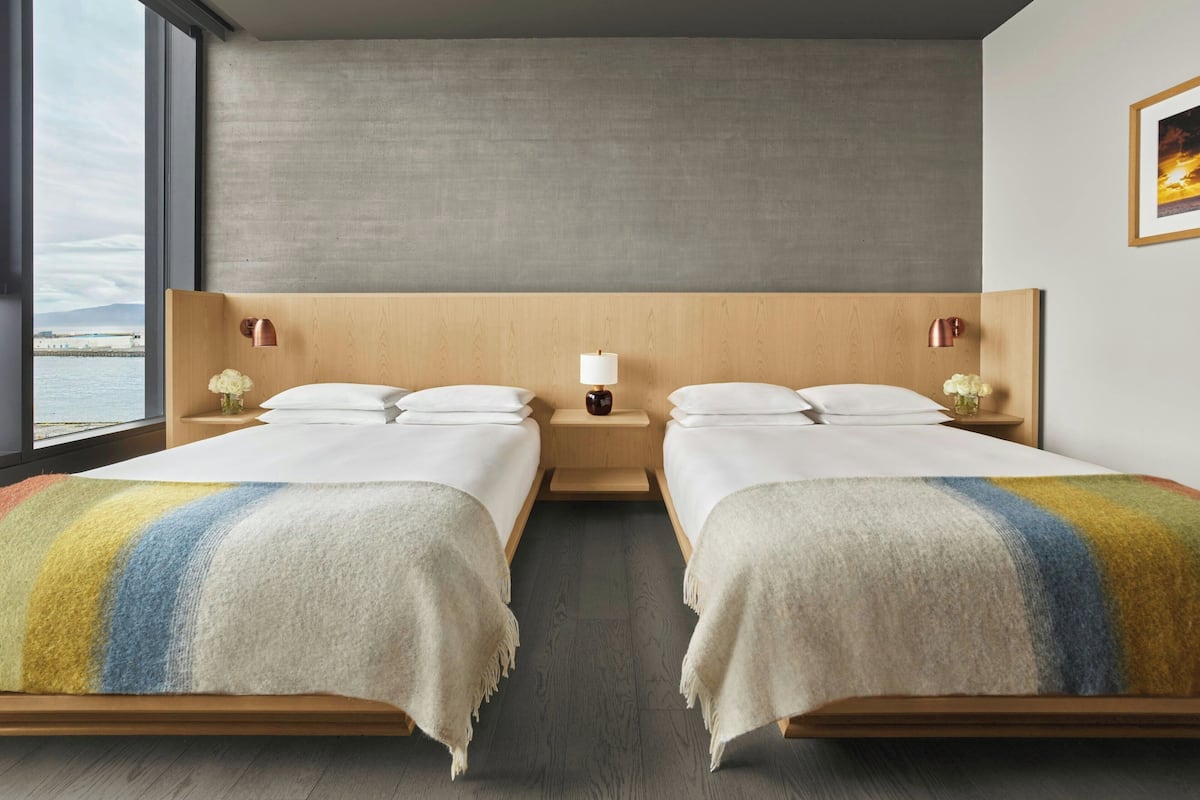 A hotel room with two beds, a view of the sea, and a large window.