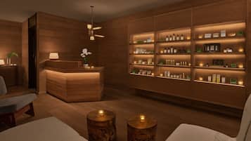 Een spa-ruimte met houten wanden, een receptiebalie, planken met producten en twee ronde houten krukken met kaarsen.