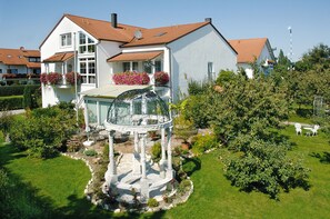 A white house with a red roof, a garden with a gazebo, and a clear sky. - Pension Martinus (Neustadt an der Donau)