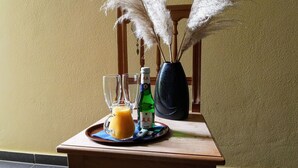 A wooden table with a tray holding a glass of orange juice, a bottle of beer, and a vase with dried plants. - Pension Martinus (Neustadt an der Donau)