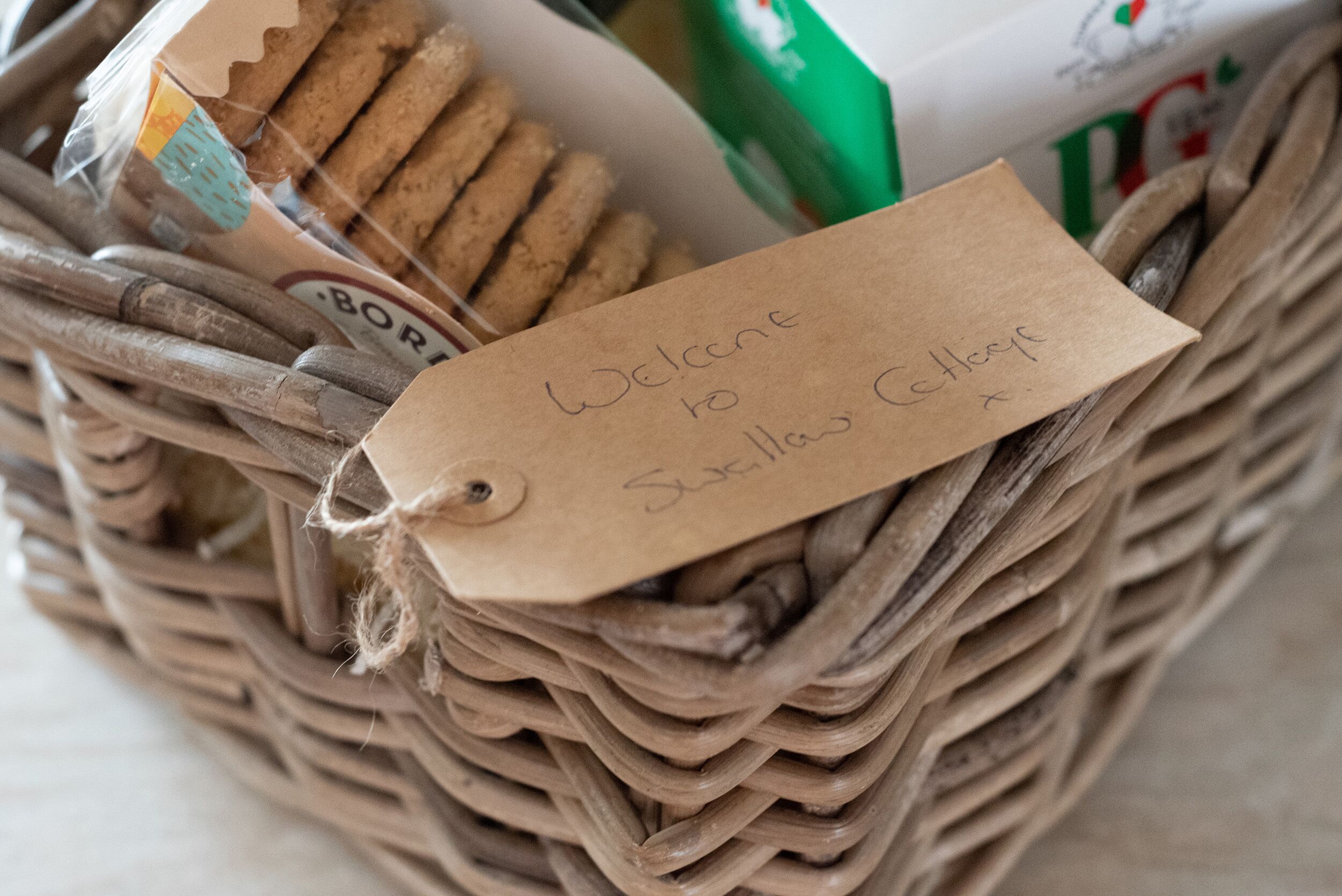 A wicker basket with a tag that reads "Welcome to Suxilla Cottages."