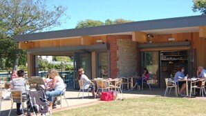 An outdoor seating area with tables and chairs, a brick wall, and a building entrance. - Spacious House for 10 Near Town & Beach (Bognor Regis)