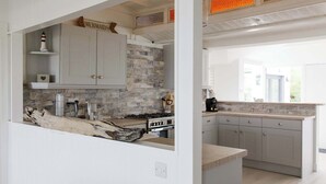 Een moderne keuken met grijze kastjes, een betegelde achterwand en een groot kookeiland met een rustieke houten kern.